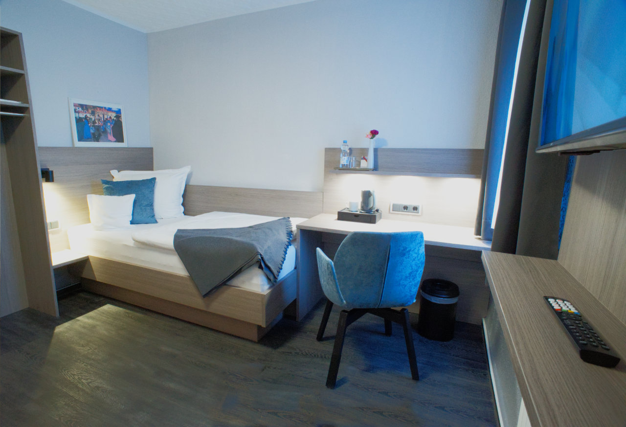 Klassik-Zimmer mit Bett, blauem Stuhl und Schreibtisch