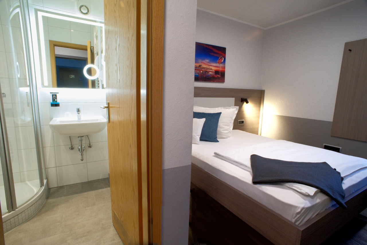 Zimmer mit Blick ins Bad mit beleuchtetem Spiegel