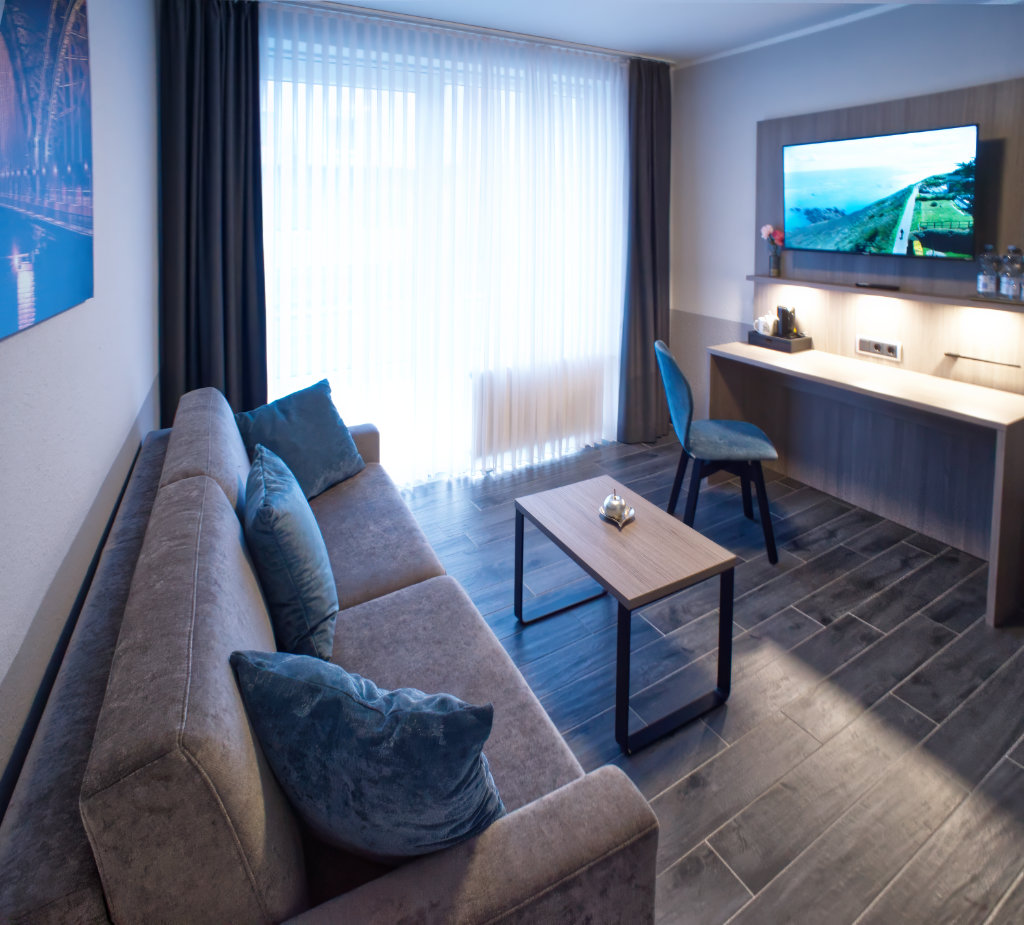 Komfort-Zimmer mit Sofa, Couchtisch und Wandfernseher