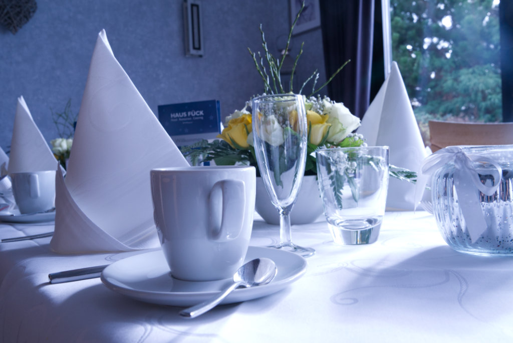 Weiß gedeckter Tisch mit Kaffeetassen und Blumen